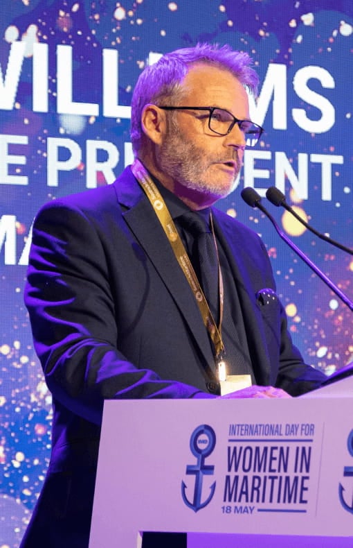 A man in business suit standing at the podium and giving speech.