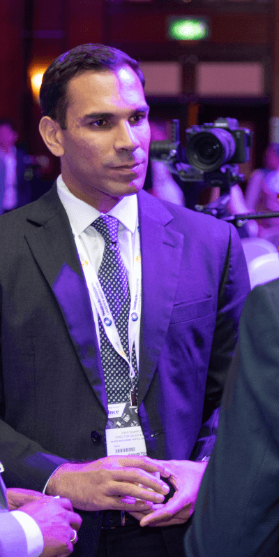 A professional man in a suit with a conference badge